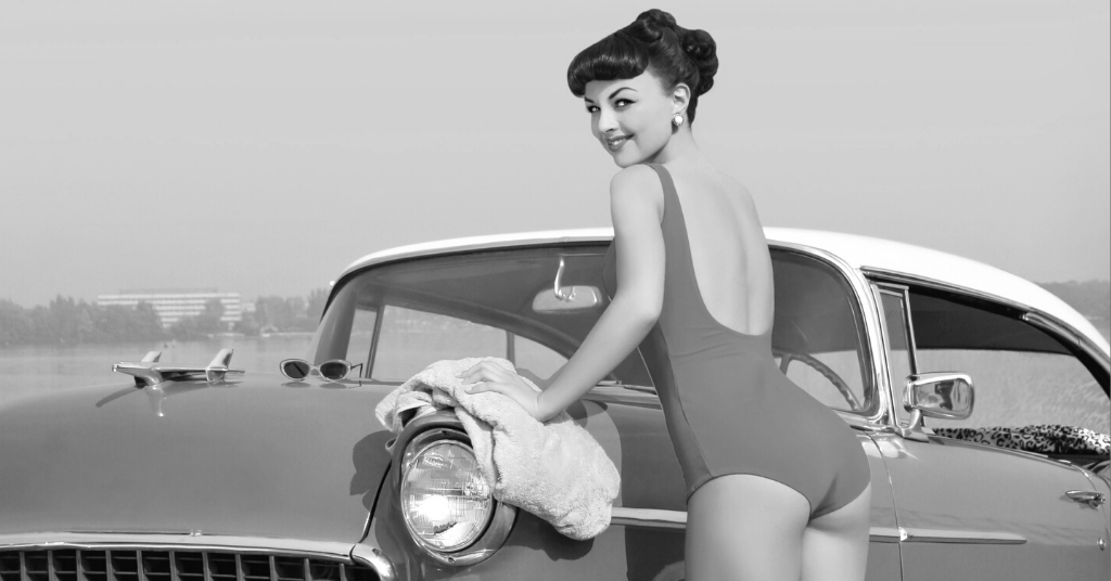 Woman posing in 50s bathing suit washing car