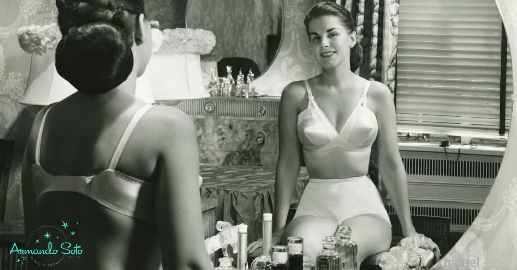Woman in 1950's lounge wear smiles into her bedroom mirror. (model)