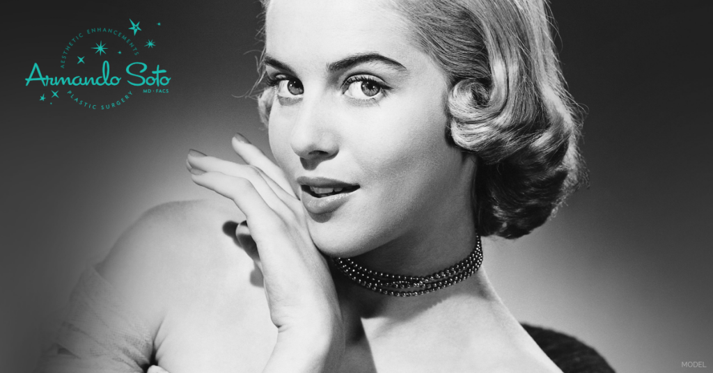 Woman smiling with her hand on her chin. (Model) Aesthetic Enhancements Plastic Surgery & Laser Center: Armando Soto, MD Logo